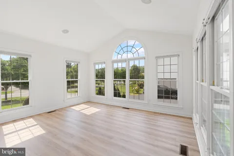 an empty room with windows wooden floor and a fireplace