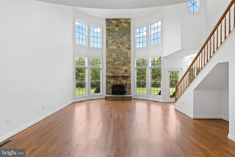 a view of an empty room with wooden floor fireplace and a window