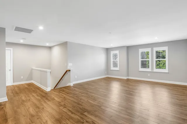 a view of empty room with wooden floor and window
