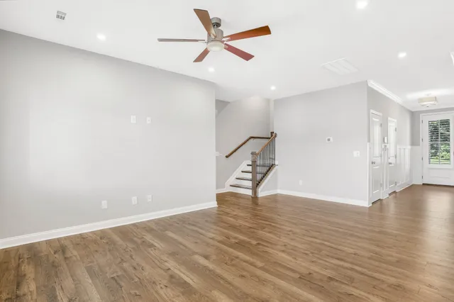 an empty room with wooden floor and a ceiling fan