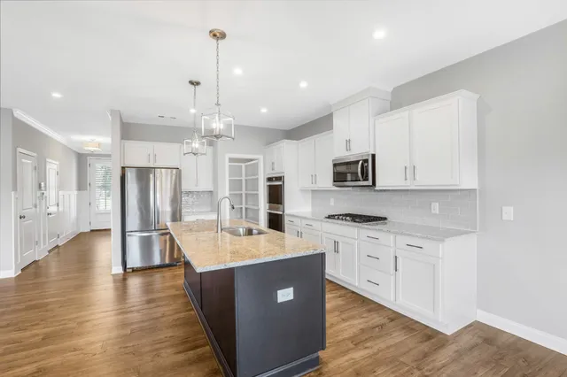 a large kitchen with stainless steel appliances kitchen island granite countertop a stove oven and a refrigerator