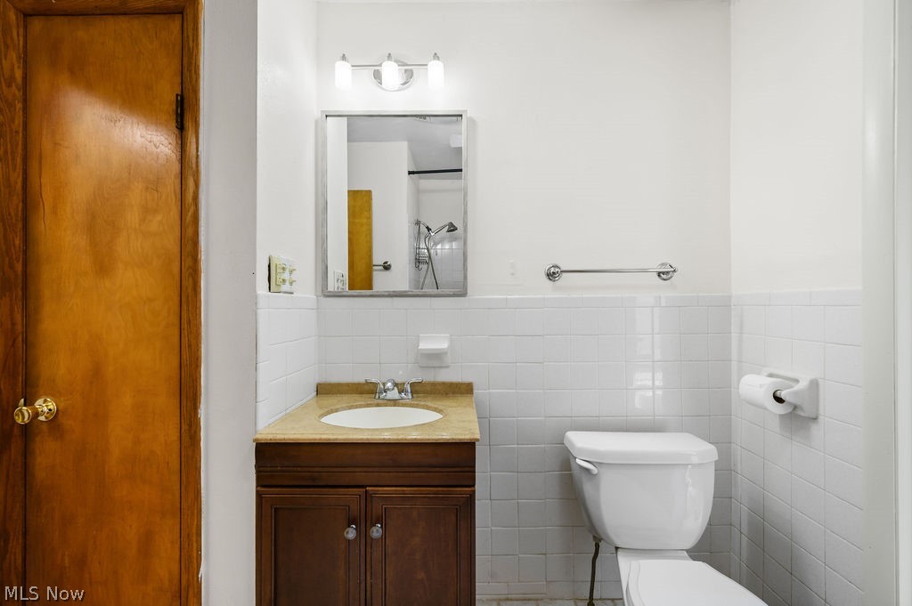 11363 Dupont Road Washington, WV 26181 - Photo 19 of 42 Wood-finish door, white ceramic wall tile, vanity with a light-colored countertop, and a built-in medicine cabinet