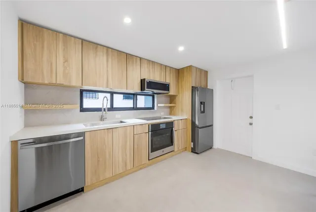 a kitchen with a sink cabinets stainless steel appliances and a window