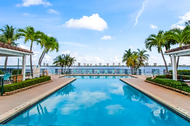 a view of swimming pool with a yard and palm trees