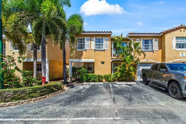a view of a brick house with a large windows plants and large tree