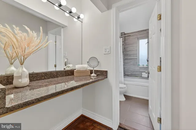 a bathroom with a granite countertop sink a toilet and a shower