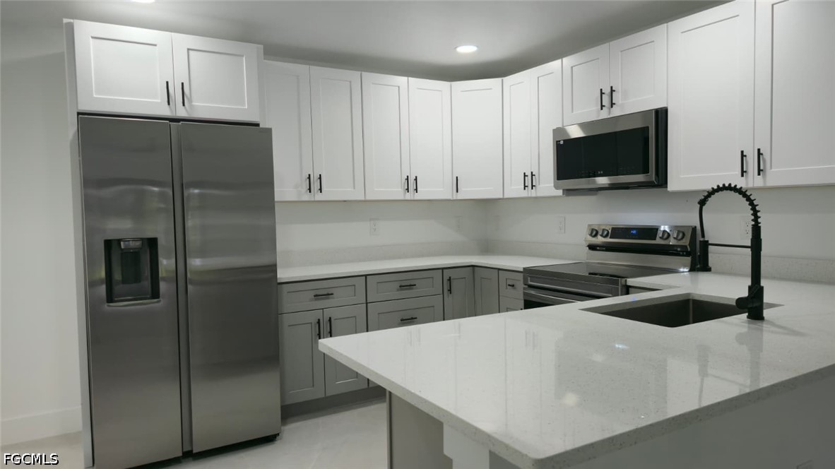 4429 26th Street Southwest Lehigh Acres, FL 33973 - Photo 2 of 16 a kitchen with stainless steel appliances a refrigerator sink and white cabinets