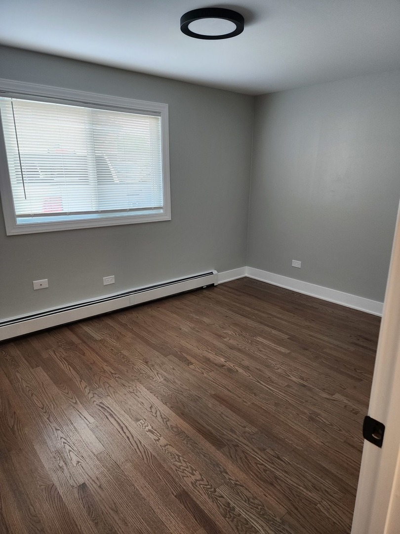 9421 South Roberts Road, Unit 1NW Hickory Hills, IL 60457 - Photo 8 of 12 an empty room with wooden floor and windows