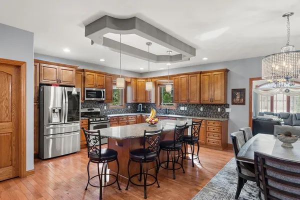 a dining area with stainless steel appliances kitchen island granite countertop a dining table and chairs