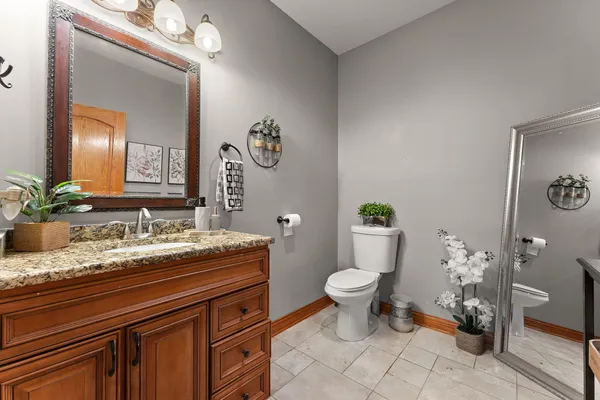 a bathroom with a granite countertop toilet sink and mirror