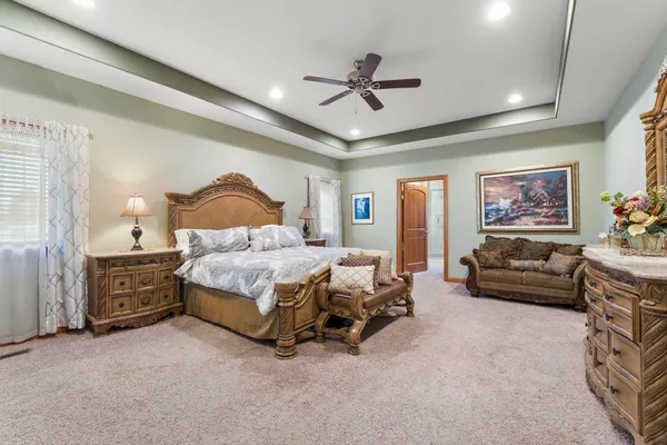 a spacious bedroom with a bed a couch and a chandelier