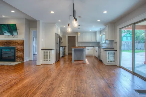 a open kitchen with stainless steel appliances granite countertop a refrigerator a stove top oven and a wooden floors