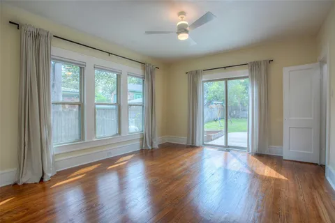 a view of an empty room with wooden floor and a window
