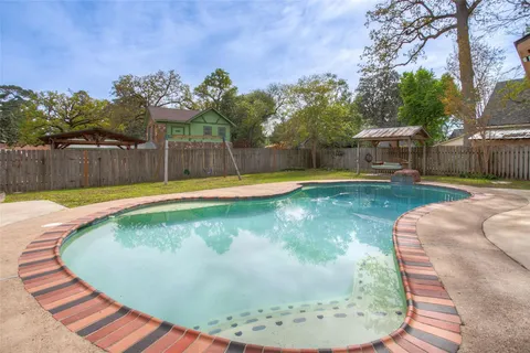 a view of a swimming pool with a yard and wooden fence