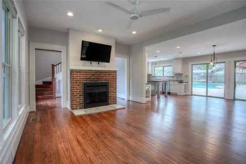 a view of a livingroom with fireplace wooden floor and a kitchen space