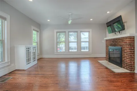 an empty room with wooden floor fireplace and windows