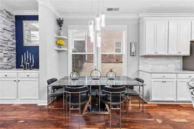 a kitchen with stainless steel appliances granite countertop a table chairs sink and cabinets