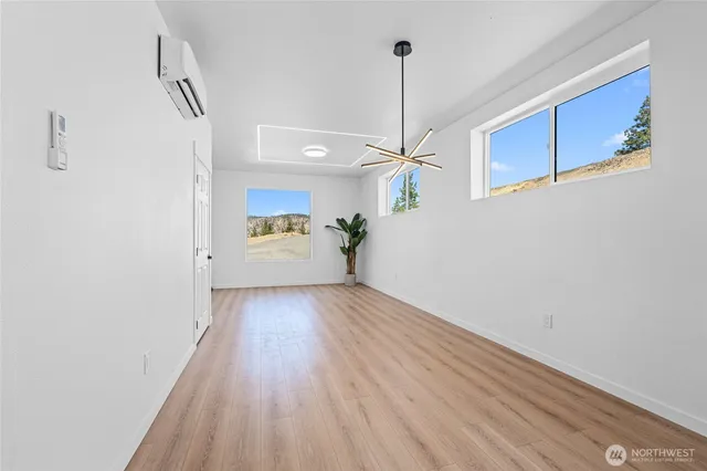 a view of an empty room with a window and wooden floor