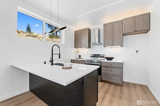 a kitchen with stainless steel appliances a sink dishwasher a refrigerator and cabinets with wooden floor