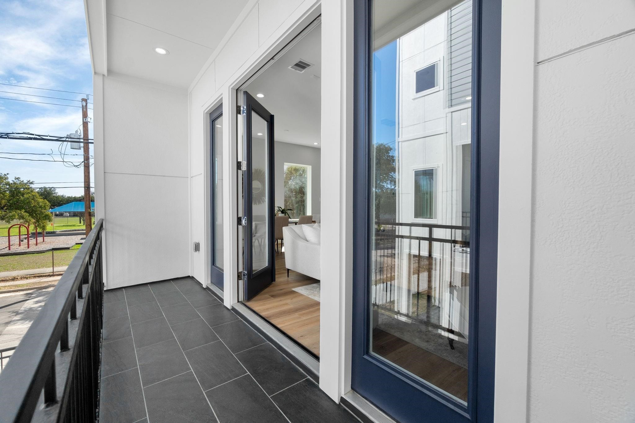 903 Quitman Street, Unit B Houston, TX 77009 - Photo 22 of 23 Private covered balcony with sleek tile flooring and modern railing, offering a seamless indoor-outdoor connection through double glass doors.