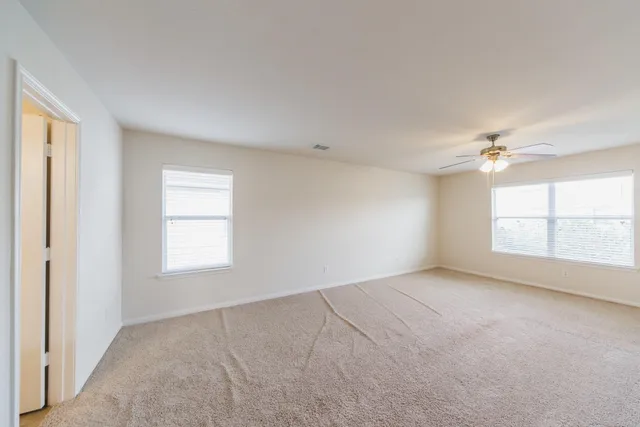 a view of a big room with windows and chandelier fan