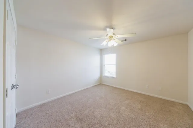 an empty room with a chandelier fan and windows