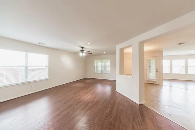 a view of an empty room with wooden floor and a window