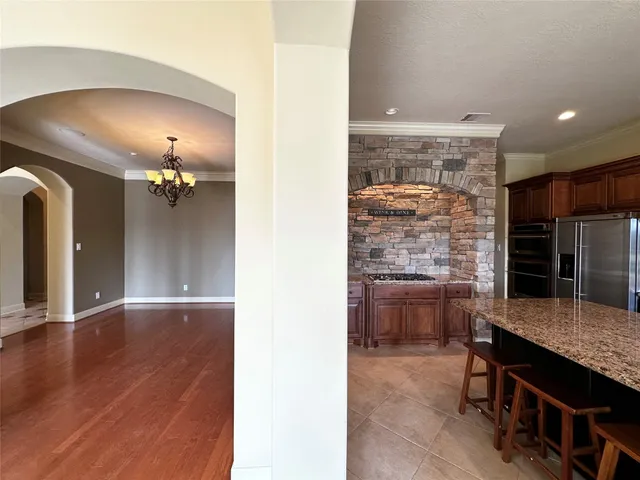 an empty room with wooden floor and kitchen view