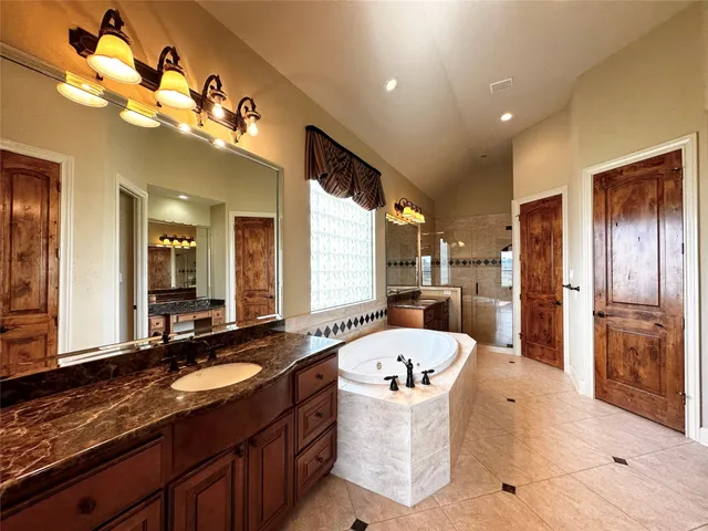 a spacious bathroom with a tub a double vanity sink a mirror and a bathtub