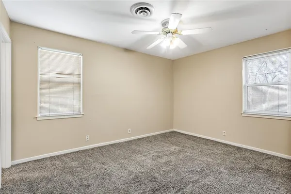 an empty room with windows and fan