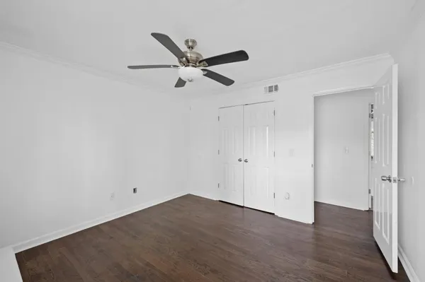 an empty room with wooden floor and a ceiling fan