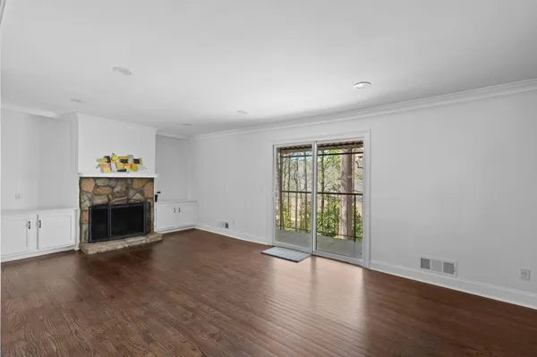 an empty room with wooden floor fireplace and windows