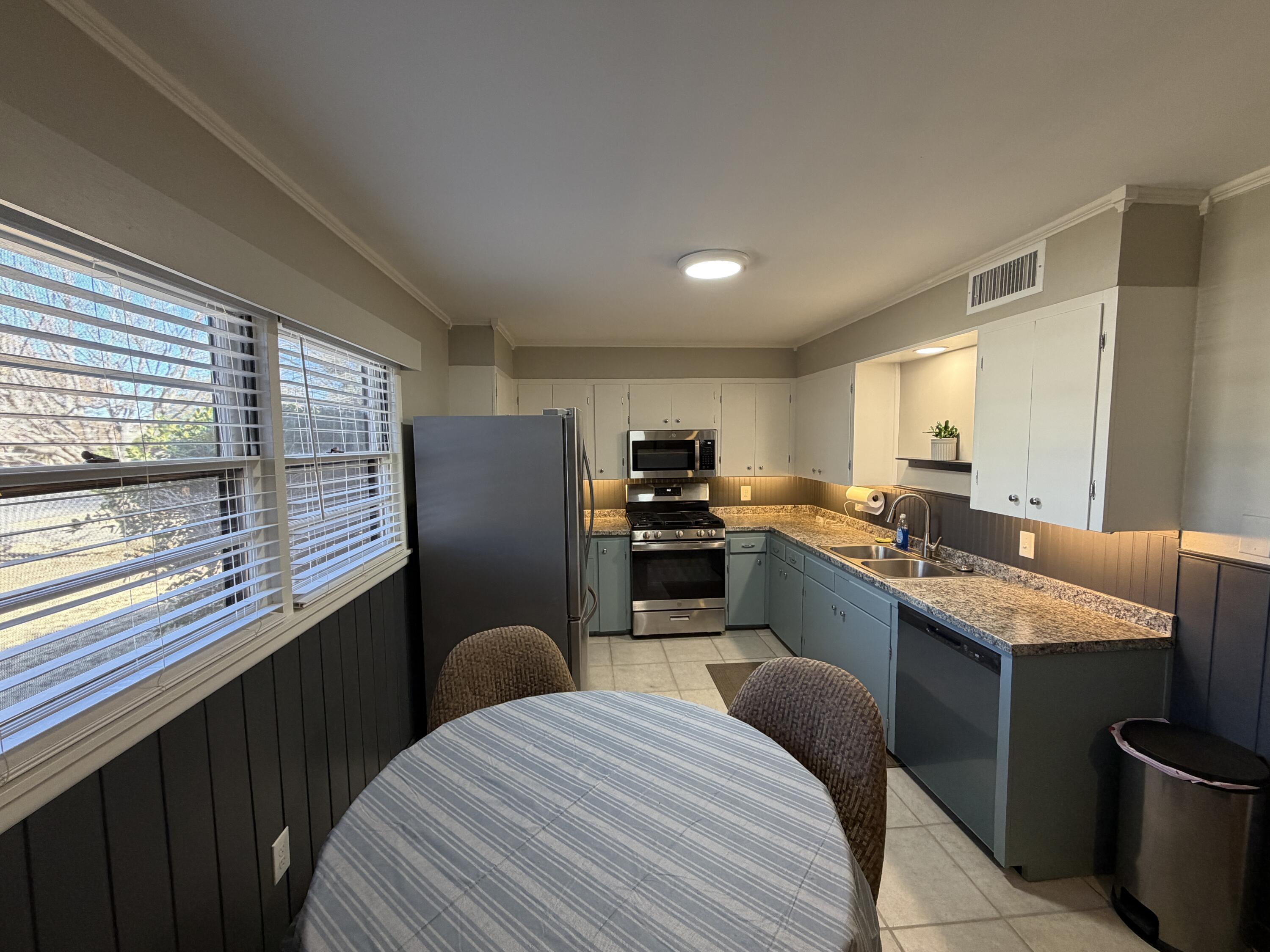 3113 38th Street Lubbock, TX 79413 - Photo 4 of 22 a kitchen with stainless steel appliances granite countertop a refrigerator a sink dishwasher a stove and white countertops with wooden floor