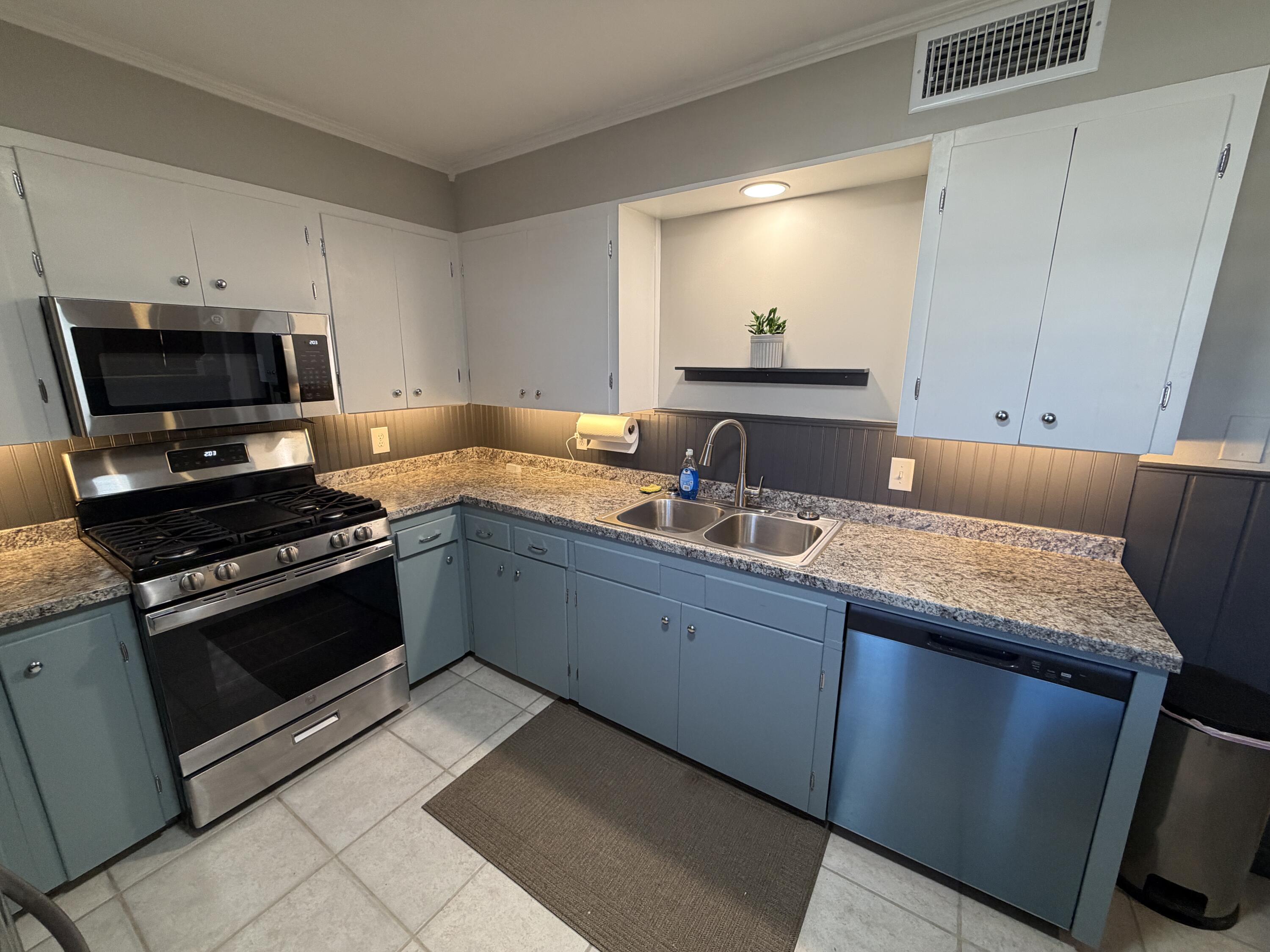 3113 38th Street Lubbock, TX 79413 - Photo 5 of 22 a kitchen with sink a microwave a stove and cabinets