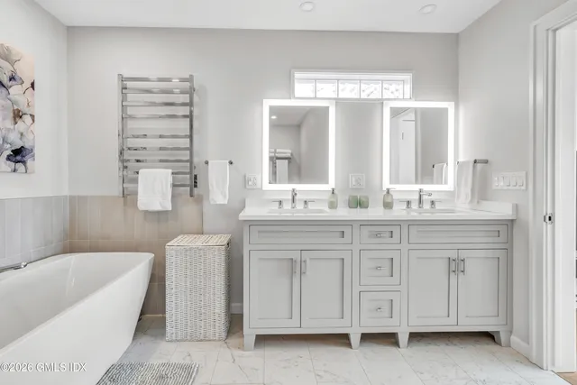 a bathroom with a granite countertop sink a large mirror a bathtub and next to a window