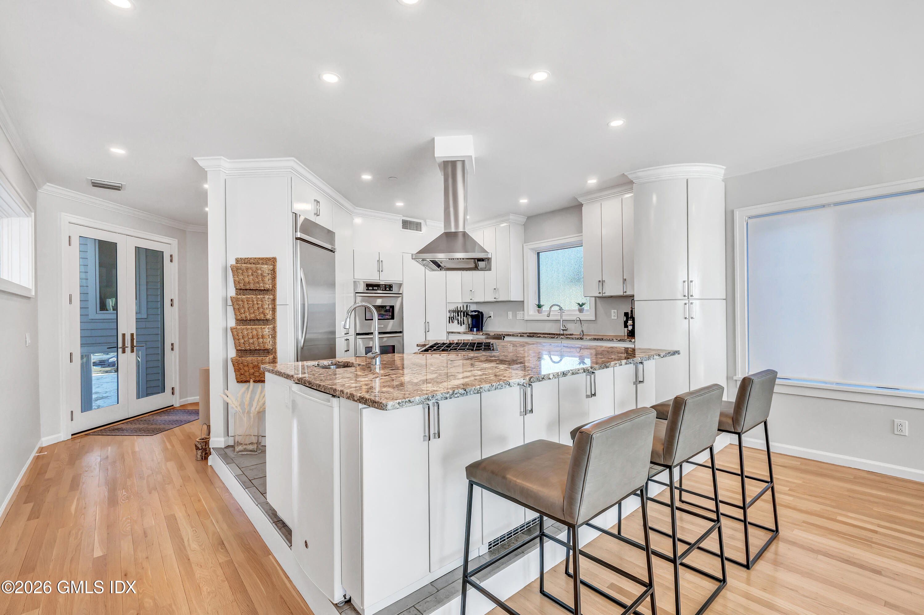 1053 Fairfield Beach Road Fairfield, CT 06824 - Photo 4 of 40 a kitchen with stainless steel appliances kitchen island granite countertop a dining table chairs and white cabinets