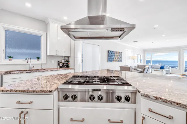 a kitchen with granite countertop stainless steel appliances sink stove and cabinets