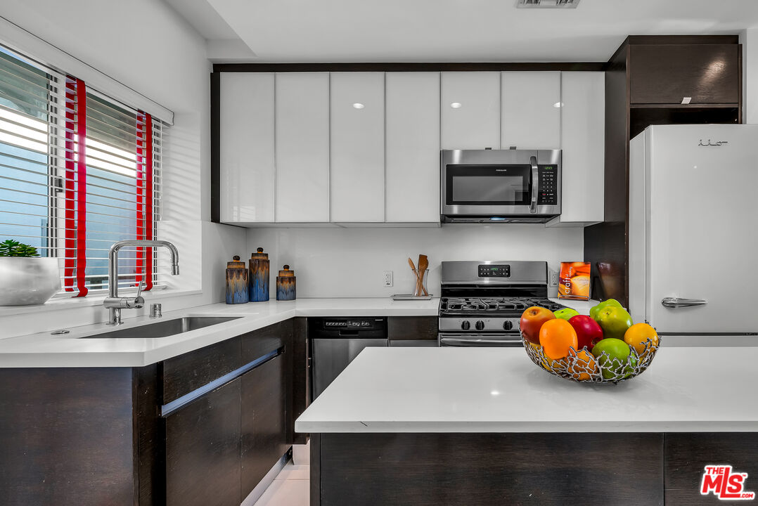 7857 West Manchester Avenue, Unit 201 Playa del Rey, CA 90293 - Photo 15 of 28 a kitchen with stainless steel appliances a sink a stove a microwave a sink and cabinets