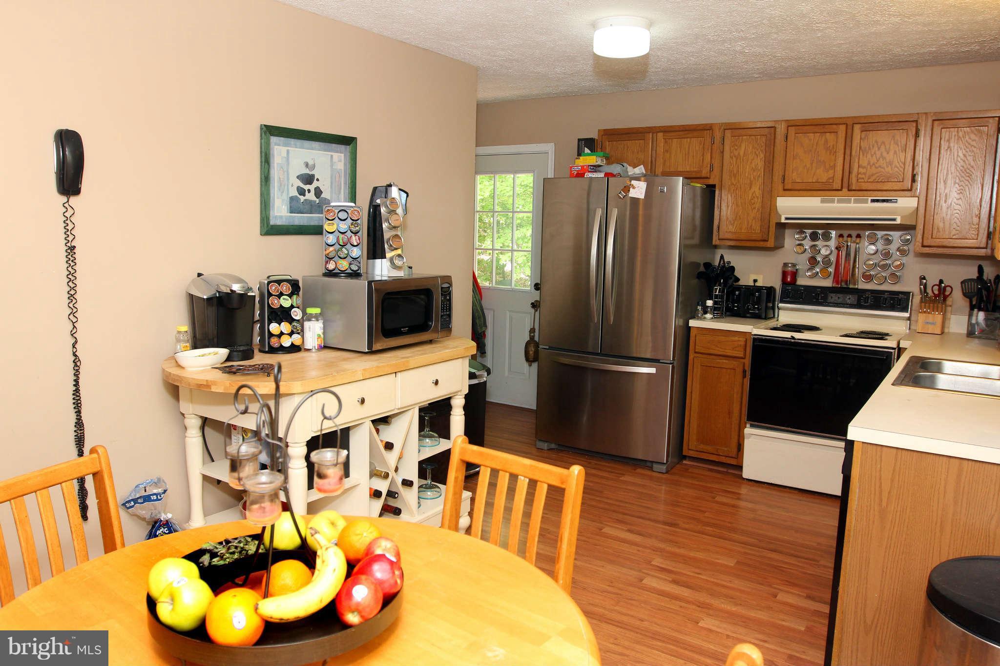 467 Redwood Road Lusby, MD 20657 - Photo 4 of 20 a kitchen with stainless steel appliances granite countertop a refrigerator a stove a sink dishwasher and a dining table with wooden floor