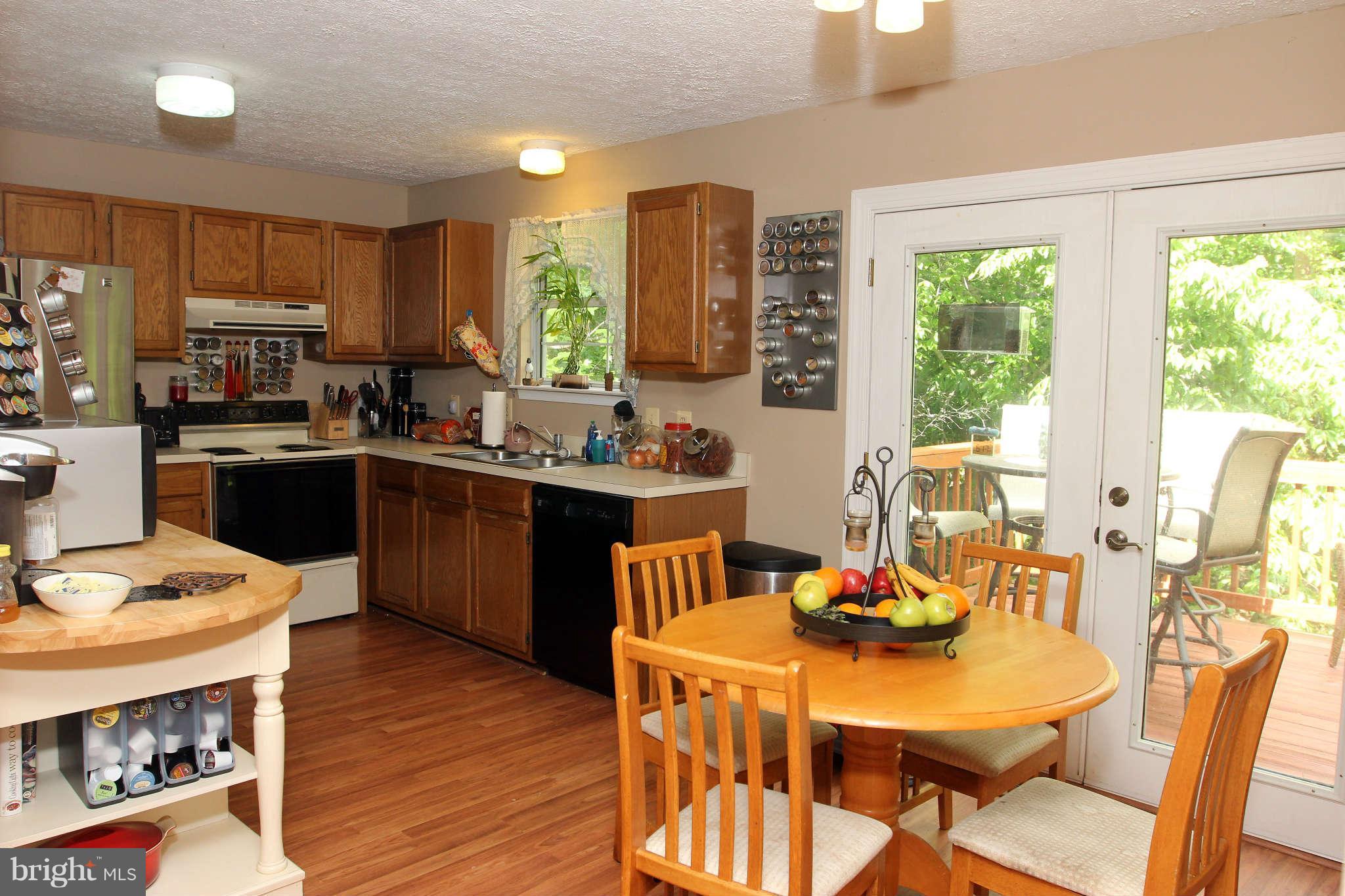 467 Redwood Road Lusby, MD 20657 - Photo 5 of 20 a kitchen with stainless steel appliances granite countertop a stove a refrigerator a sink dishwasher a dining table and chairs with wooden floor