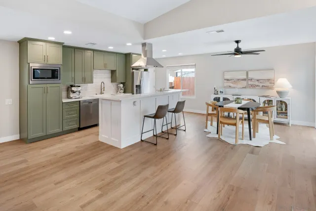 a kitchen with stainless steel appliances a dining table chairs stove refrigerator and cabinets