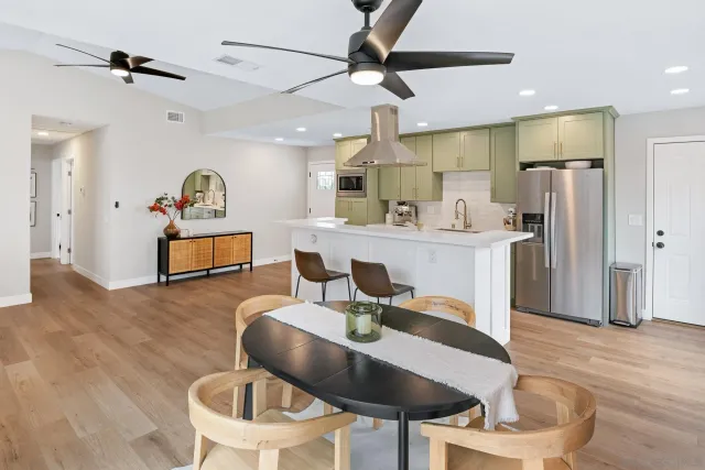 a kitchen with stainless steel appliances kitchen island granite countertop a dining table chairs refrigerator and a sink