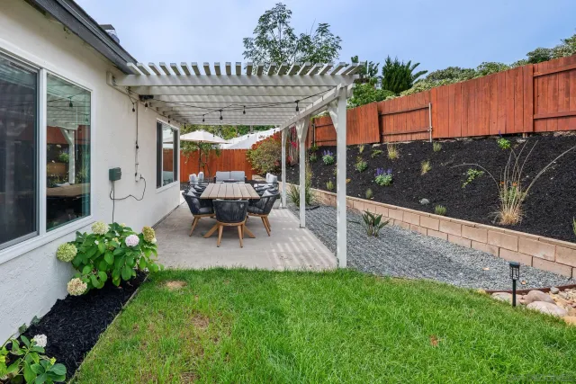 a backyard of a house with table and chairs under an umbrella