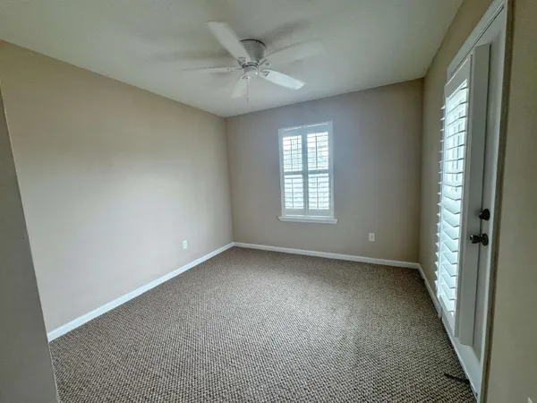 an empty room with windows and chandelier fan
