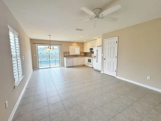 a large white kitchen with granite countertop a large window and a refrigerator