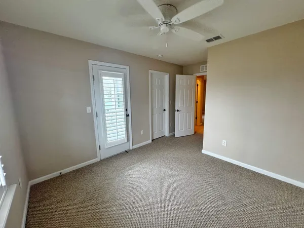 an empty room with windows and fan