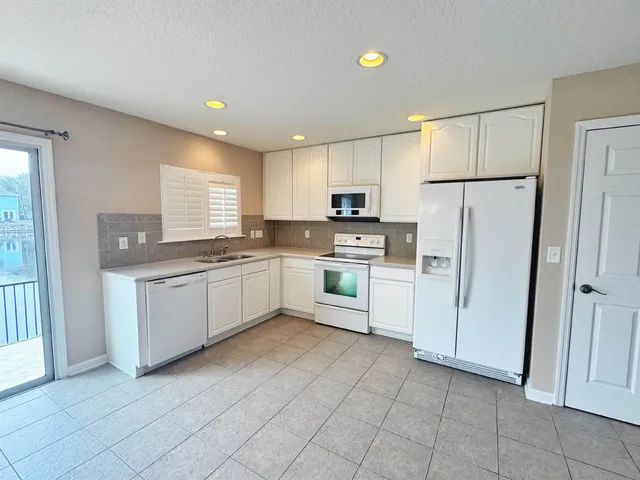 a kitchen with white cabinets and white appliances