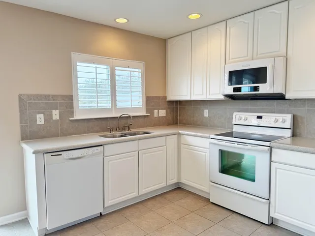 a kitchen with white cabinets and white appliances