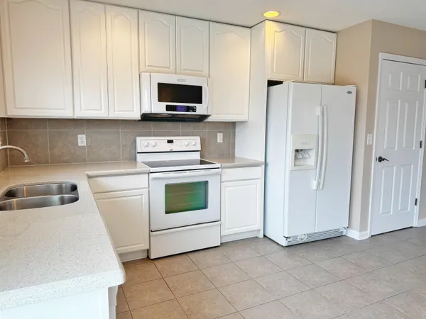a kitchen with white cabinets and white appliances