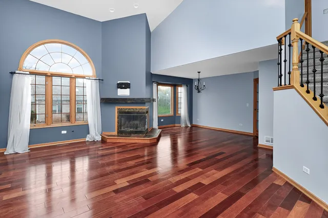 a view of an empty room with chandelier fan and fire place